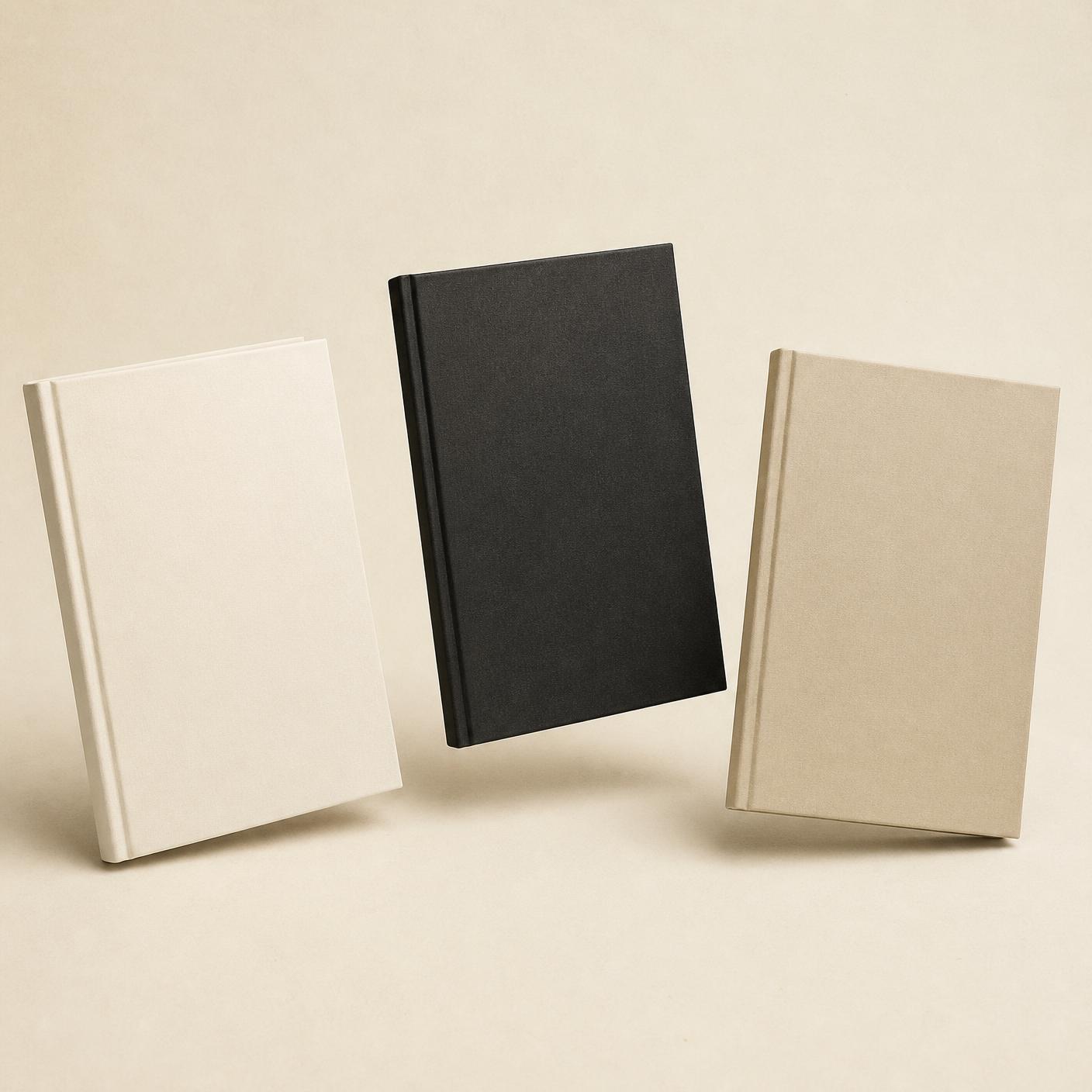 Three blank hardcover book mockups in bone white, charcoal and sand